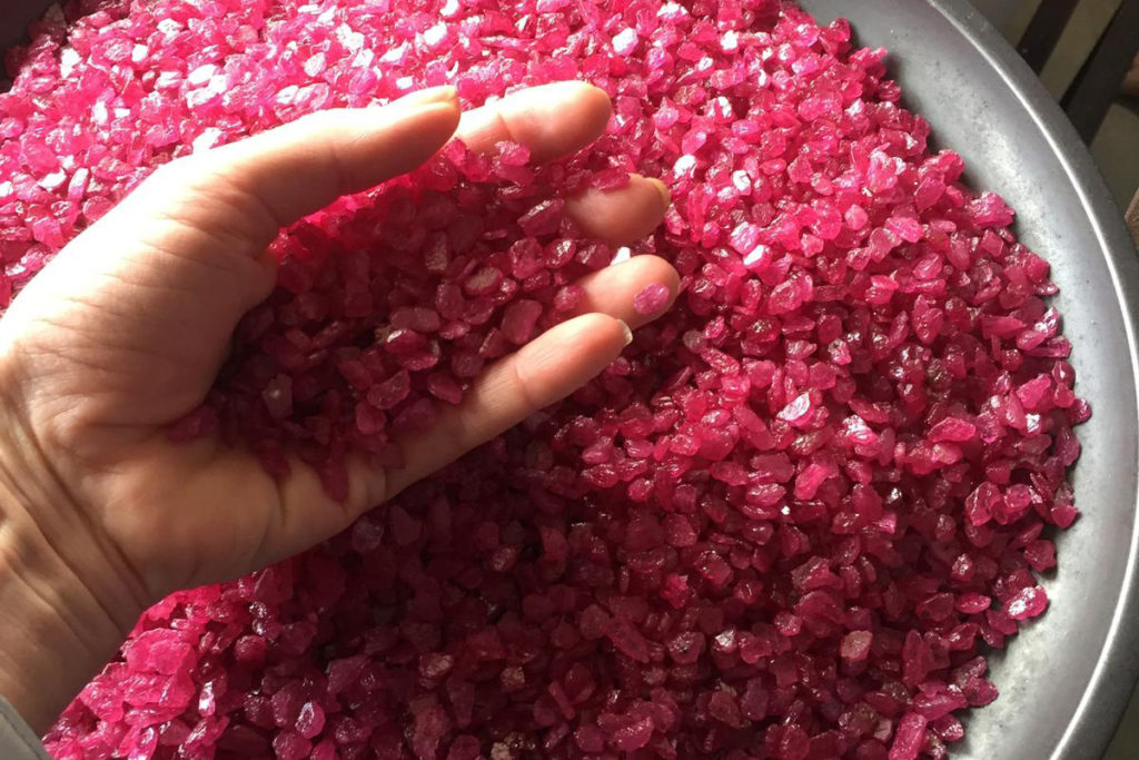 Someone dipping their hand into a bucket of rubies 