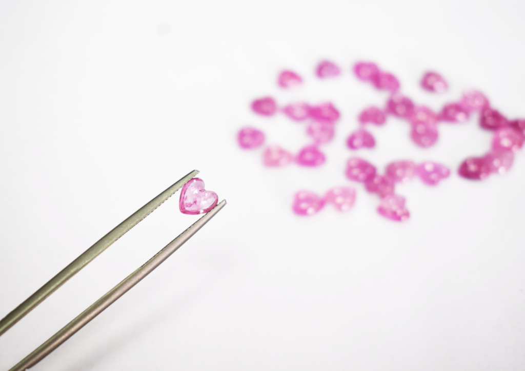 Pink hearted rubies being held with tweezers